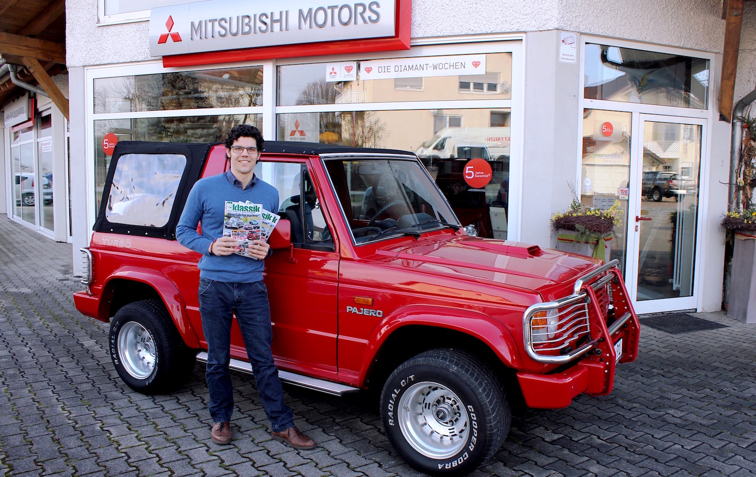 Stolz posiert Johannes Wohlmannstetter vor seinem Mitsubishi Pajero Canvas Top, in der Hand die AUTO BILD KLASSIK, in der sein Fahrzeug erschien.